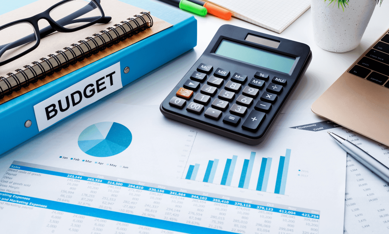 Calculator, charts, and notebook labeled 'Budget' on a desk, symbolizing financial planning and budgeting strategies.