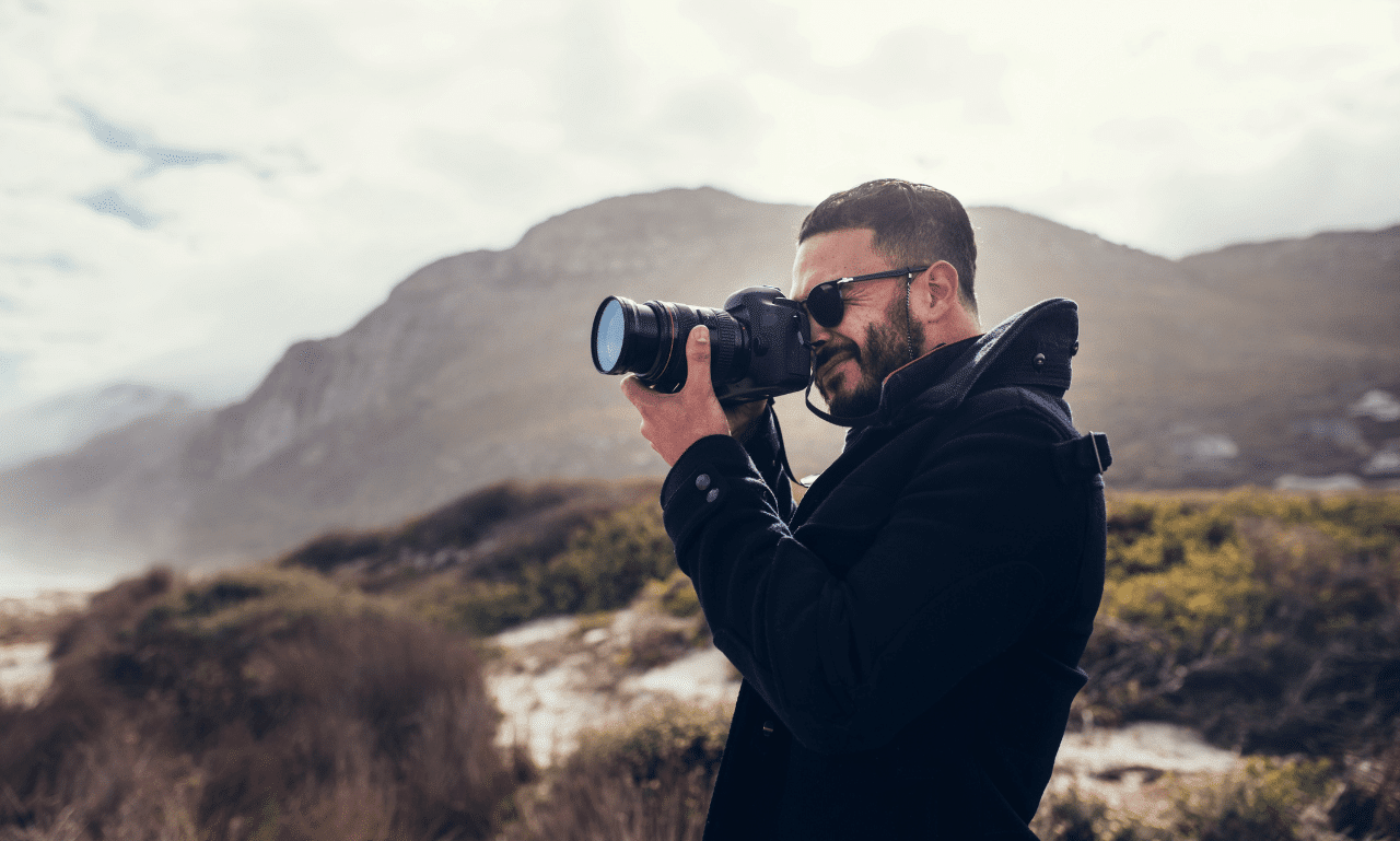 A cameraman capturing a scenic view, with the photographer in the frame to show mindfulness