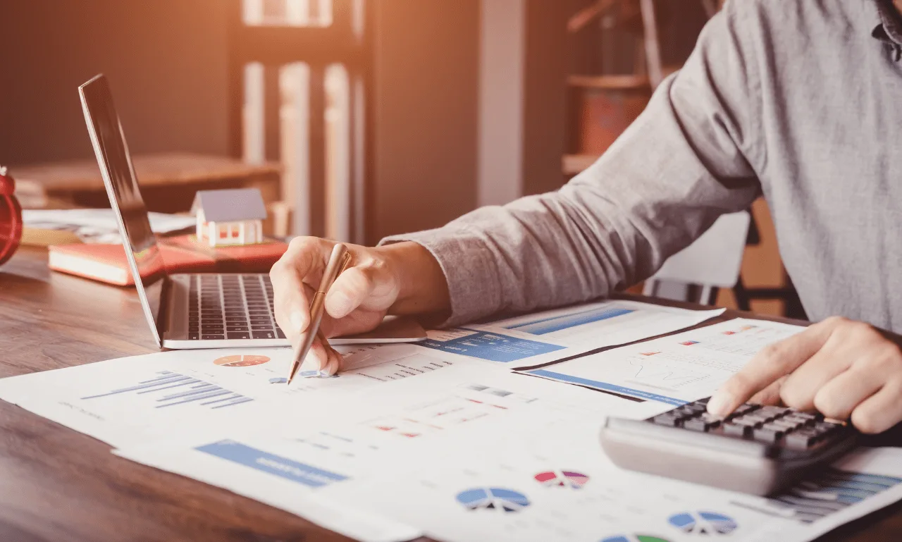 Person using a calculator and reviewing charts and graphs for budget planning